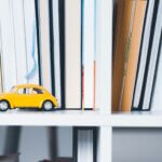 yellow Volkswagen beetle toy on wooden shelf